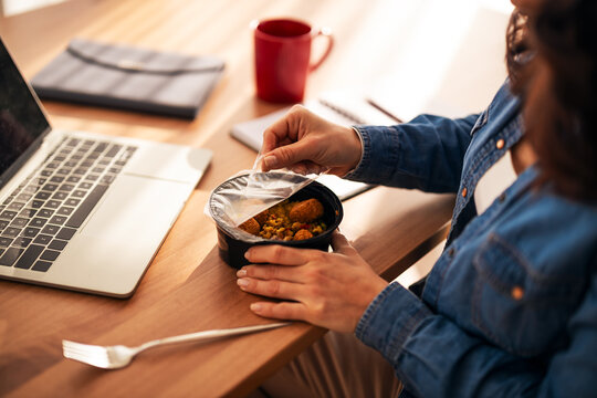 Person taking and eating delicious takeaway lunch at the desk
