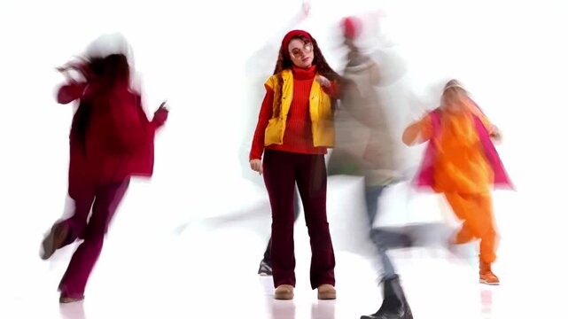 Woman in winter clothing with motion blur people around. Concept of pause in daily routine, personal style, calm presence, everyday lifestyle contrast, individuality in fast urban rhythm.