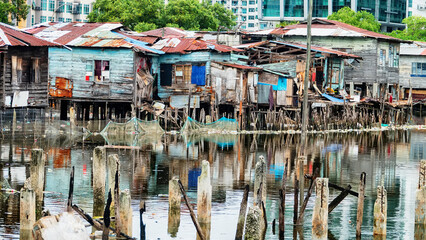 Kota Kinabalu, Malaysia. Illegal Filipino immigrants Bajau live in pile-buildings settlement, slum. Some houses been demolished, residents evicted. Modern high-rise buildings stand in background