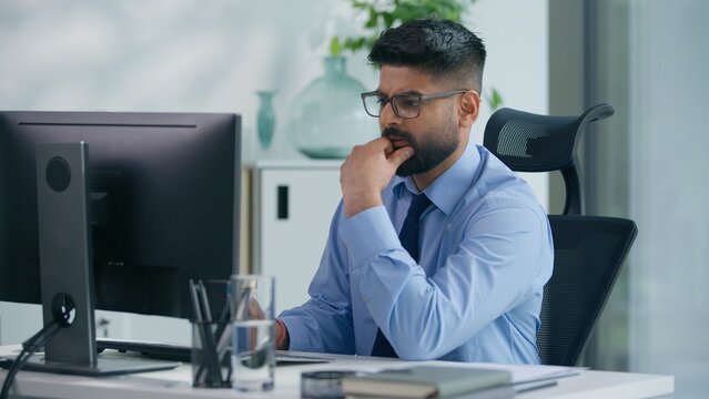 Indian businessman Arabian business man ethnic male worker guy professional entrepreneur working in office typing computer thinking ponder think idea focused solving busy job online at workplace table