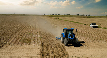 Obraz premium Tractor ploughing a large field. Aurtumn season. 