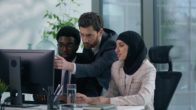 Multicultural business colleagues collaborating in modern office multiracial co-workers working African American male woman in hijab and Caucasian man looking at computer discussing teamwork startup - Powered by Adobe