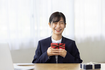 Smiling Young Businesswoman Holding Gift Box at Office Desk