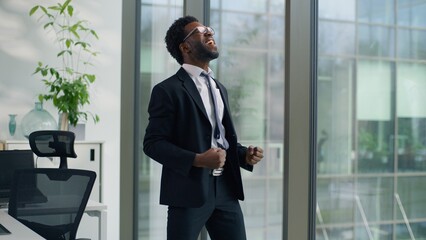 Business in office happy winner African American businessman man male employer entrepreneur winning victory achievement reaction dancing jumping celebrate working success job achieve startup satisfied