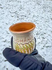 Hand holding romanian pottery on snowy ground