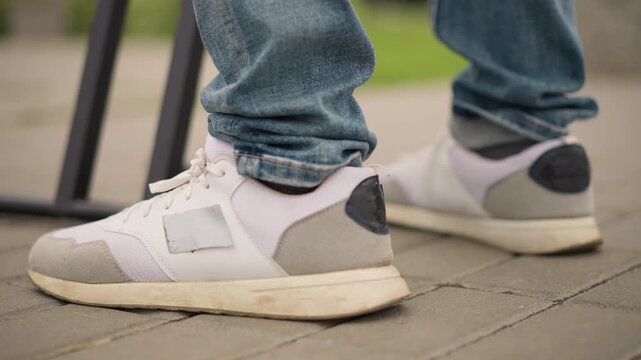closeup sneaker stepping on tiled pavement, denim cuff over trainer, foot engaging effects pedal near stand, rhythmic testing for live set, pulsing tempo and upbeat urban energy captured for music