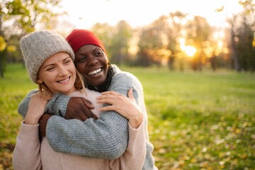 Fototapeta premium Diverse women friends hugging outdoors at sunset in autumn