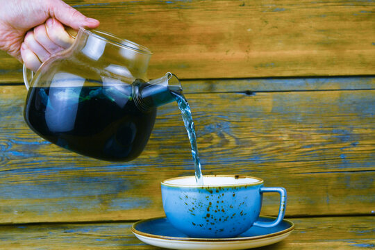 Tea is poured from a glass teapot into a cup