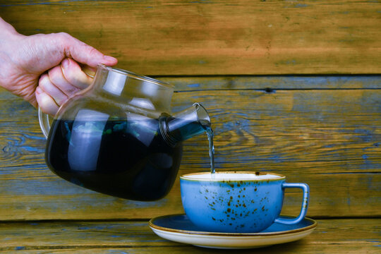 Tea is poured from a glass teapot into a cup