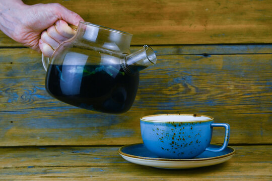 Tea is poured from a glass teapot into a cup