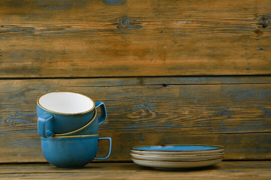 stack of blue mugs in saucers stand on a wooden table on a gray background. For design.