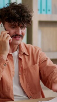 Angry mad furious Caucasian business man arguing mobile phone holding papers talking businessman argue dissatisfied with documents mistake conflict quarrel male guy talk smartphone in office company