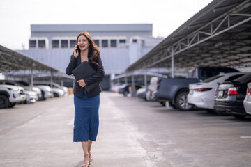 Naklejka premium Asian businesswoman walking in parking lot talking on phone