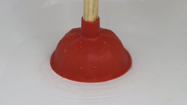Unclogging a clogged bathtub drain with a plunger, hands in rubber gloves use a sink plunger to unclog the drain hole, footage