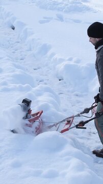 Vertical video snowblower works hard clearing a path through deep winter snow, removing accumulation after a blizzard and demonstrating the effort of seasonal outdoor maintenance