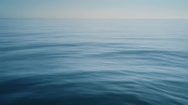 A serene shot showcasing a vast expanse of water under a soft, gradient sky. The water's surface reflects light. Horizontal lines are seen
