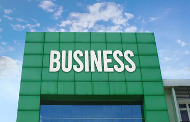 Modern green facade with a large BUSINESS sign against a cloudy blue sky.