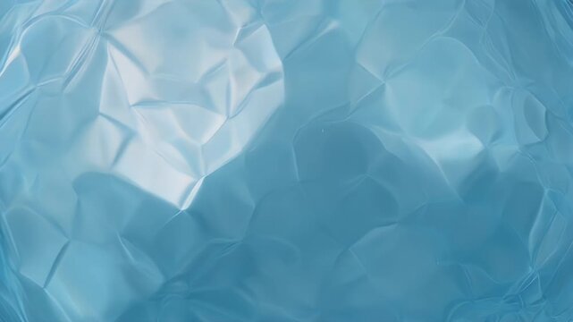 A close-up view presents a textured, iridescent, blue-toned surface resembling a translucent, folded material, with light and shadow interplay