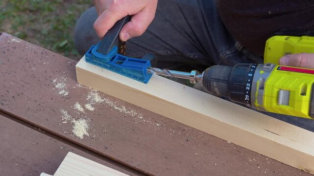 Drilling hole in wooden board using jig and power drill, woodworking process, DIY carpentry, precise drilling, home improvement, construction and craftsmanship concept