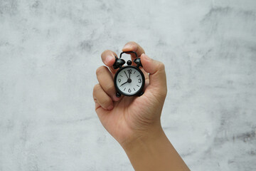 Hand holding a small alarm clock symbolizing time management and urgency.
