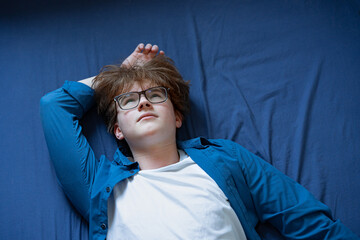 Teenage boy (zoomer) lying down in stress, burnout and mental exhaustion.