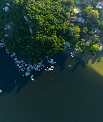 Fototapeta premium Aerial panorama of the green lush coast of the lake with buildings on the shore