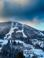 Mystical snowy Carpathian peaks under cloudy skies in the sunny weather