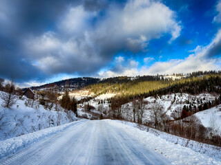 Mystical snowy Carpathian peaks under cloudy skies in the sunny weather