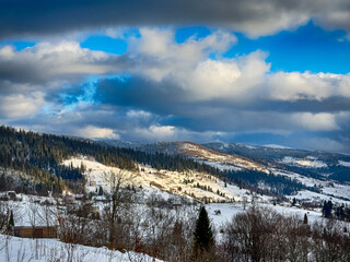 Mystical snowy Carpathian peaks under cloudy skies in the sunny weather