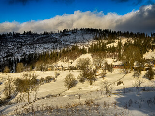 Mystical snowy Carpathian peaks under cloudy skies in the sunny weather