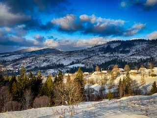 Mystical snowy Carpathian peaks under cloudy skies in the sunny weather