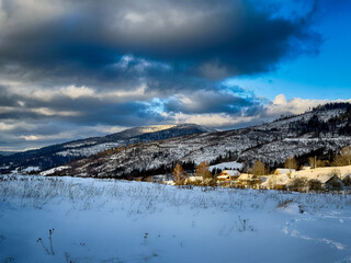 Mystical snowy Carpathian peaks under cloudy skies in the sunny weather