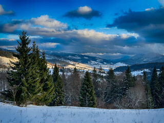 Mystical snowy Carpathian peaks under cloudy skies in the sunny weather