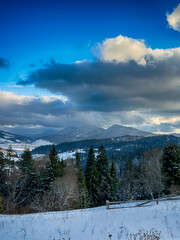 Mystical snowy Carpathian peaks under cloudy skies in the sunny weather