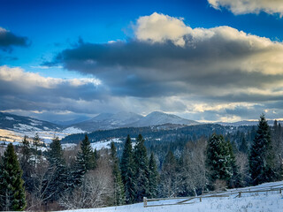 Mystical snowy Carpathian peaks under cloudy skies in the sunny weather