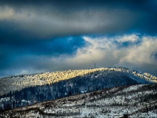 Mystical snowy Carpathian peaks under cloudy skies in the sunny weather