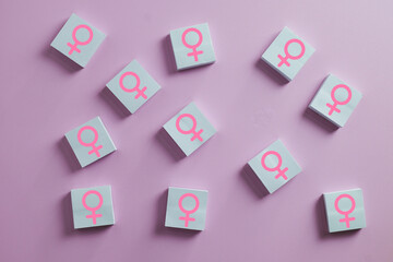 International Women's Day concept. Scattered wooden blocks with pink female gender symbol. Gender equality, girl power, feminism, and women rights support on pink background.