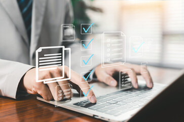 Businessman using laptop with digital document verification and approval checklist interface. Online workflow management, compliance control, paperless office and secure business process automation. © ภัทรชัย รัตนชัยวงค์