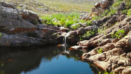 Fototapeta premium calm alpine water body with flowing stream, quiet mountain water pool featuring reflections and flowing stream