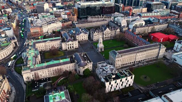 aerial drone shot capturing the trinity college university campus in the heart od the Irish capital of Dublin at sunrise with students and tourists alike wandering about with fields and trees around