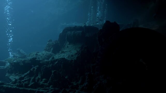 Scuba diver uses a dive torch to cut through the shadows of Hold No. 2 within the SS Thistlegorm revealing the BSA M20 motorcycles in the back of a Bedford truck.