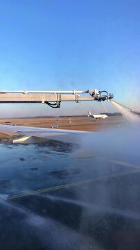 Vertical video. A deicing machine sprays an anti-icing mixture onto an airplane wing. Basel, Switzerland.