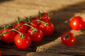 Cherry tomatoes on rustic wooden surface, bathed in warm sunlight, create fresh and vibrant scene. rich red color and natural texture evoke sense of organic simplicity