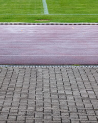 Track and field area next to a grassy sports field in a clear day setting