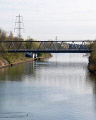 Bridge spans river with calm water and trees on banks in a sunny setting during daytime