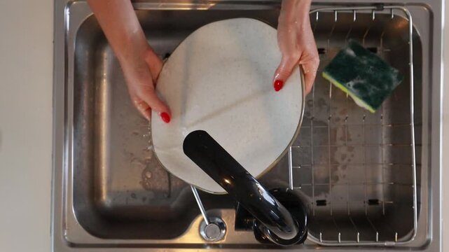 Mulher lavando lou&ccedil;a na cozinha 