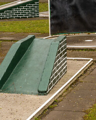 Miniature golf course with green ramps and flat surfaces for playing in a public park during daytime
