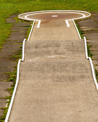 Pathway with a circular area in a park surrounded by grass and paved stones during daylight