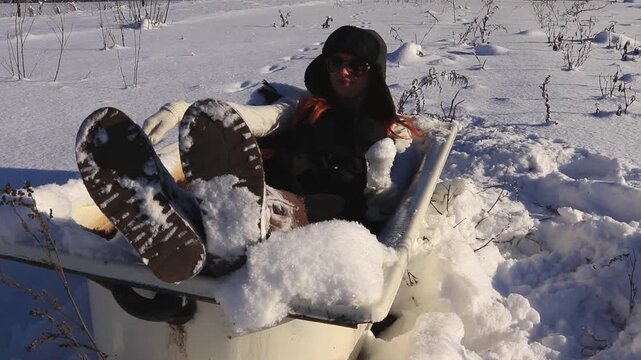Young woman in old bathtub in the middle of a snowy field enjoying the winter sun, humorous atmosphere, freedom, relaxation and creative winter mood.