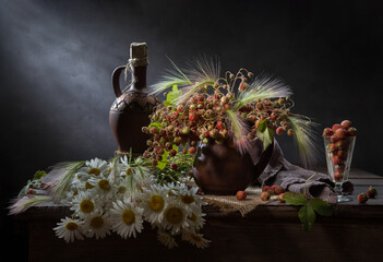 Still life with a bouquet of wild strawberries and daisies on a dark background.